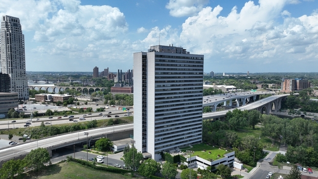 Aerial view of a tall rectangular building casting a shadow on the greenery below juxtaposed against a backdrop of elevated highways Minneapolis United States.