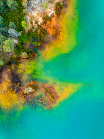 Aerial view of the vibrant mineral rich waters of the Rio Tinto showcasing striking turquoise and orange hues against the rugged tree lined riverbank in Andalusia Spain. Aerial view of the vibrant mineral rich waters of the Rio Tinto showcasing striking turquoise and orange hues against the rugged tree lined riverbank in Andalusia Spain.