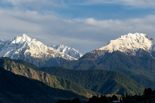 View of the snow capped peaks of Kumrat Valley rising above dense pine forests under a clear blue sky in Kumrat Valley Khyber Pakhtunkhwa Pakistan. View of the snow capped peaks of Kumrat Valley rising above dense pine forests under a clear blue sky in Kumrat Valley Khyber Pakhtunkhwa Pakistan.
