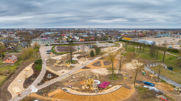 Aerial view of a park under construction with wooden play structures winding paths and surrounding residential buildings in Latvia. Aerial view of a park under construction with wooden play structures winding paths and surrounding residential buildings in Latvia.