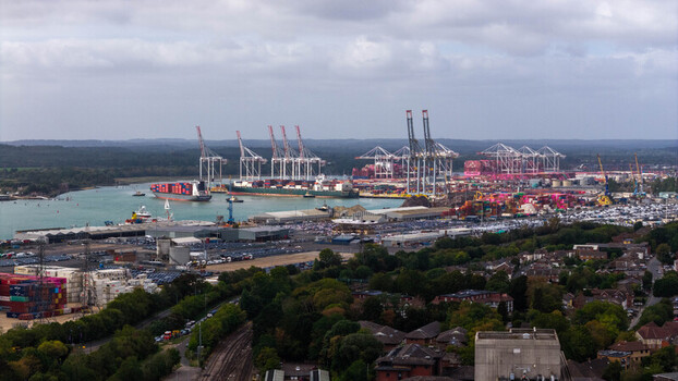 Aerial view of the Port of Southampton with large container ships gantry cranes and stacks of colorful shipping containers at the industrial waterfront in Southampton England United Kingdom. Aerial view of the Port of Southampton with large container ships gantry cranes and stacks of colorful shipping containers at the industrial waterfront in Southampton England United Kingdom.