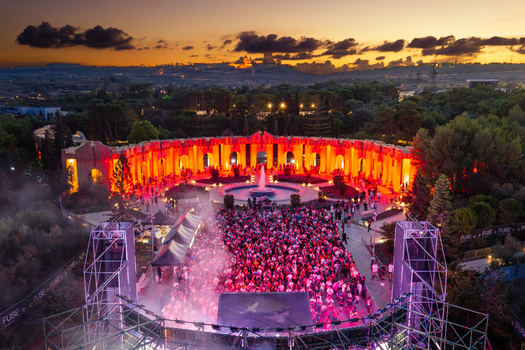 Attard Northern Region Malta 20 September 2026 Aerial view of Park Nazzjonali Ta Qali during a music festival at night with a large crowd red stage lighting fountain and sunset sky. Attard Northern Region Malta 20 September 2026 Aerial view of Park Nazzjonali Ta Qali during a music festival at night with a large crowd red stage lighting fountain and sunset sky.