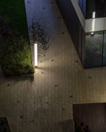 Aerial view of a modern office building in the financial center at night with illuminated walkways parked bicycles and glass architecture in Warsaw Masovian Voivodeship Poland.