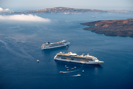 View of two large cruise ships anchored in the caldera bay with smaller boats nearby and the volcanic cliffs of Santorini in the background Fira Greece. View of two large cruise ships anchored in the caldera bay with smaller boats nearby and the volcanic cliffs of Santorini in the background Fira Greece.
