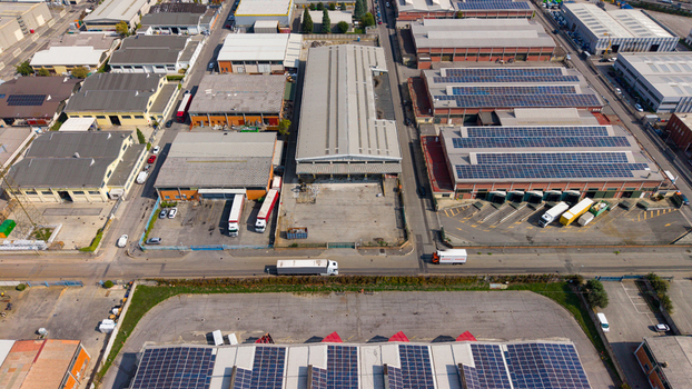 Aerial view of an industrial and logistics complex featuring warehouses with rooftop solar panels loading docks and trucks in San Giuliano Milanese Lombardy Italy. Aerial view of an industrial and logistics complex featuring warehouses with rooftop solar panels loading docks and trucks in San Giuliano Milanese Lombardy Italy.