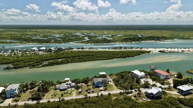 Aerial view of Matanzas Inlet with coastal houses lush vegetation turquoise water and boats under a blue sky in St. Johns County Florida United States. Aerial view of Matanzas Inlet with coastal houses lush vegetation turquoise water and boats under a blue sky in St. Johns County Florida United States.