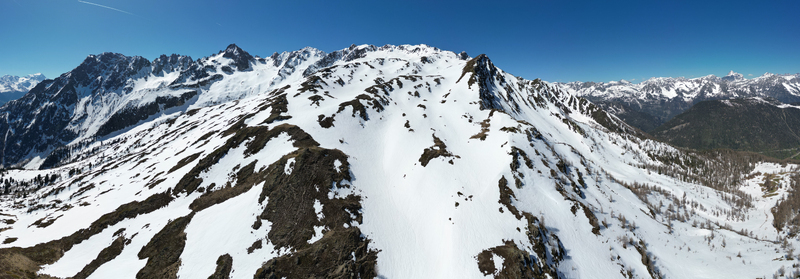 Aerial view of Pointe Ronde mountain peak with snow covered slopes and rocky ridges under a clear blue sky in Trient Valais Switzerland.