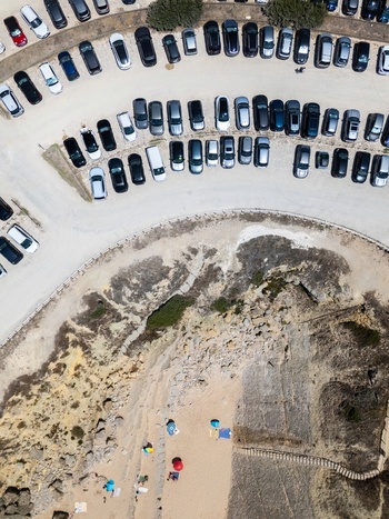 Aerial view of Praia do Guincho with a crowded parking lot situated above the sandy beach and rocky cliffs in Cascais Lisbon Portugal. Aerial view of Praia do Guincho with a crowded parking lot situated above the sandy beach and rocky cliffs in Cascais Lisbon Portugal.
