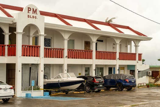 San Jose Tinian Northern Mariana Islands 05 July 2026 View of the P.M. Building in San Jose with a boat on a trailer and parked cars in front under an overcast sky. San Jose Tinian Northern Mariana Islands 05 July 2026 View of the P.M. Building in San Jose with a boat on a trailer and parked cars in front under an overcast sky.