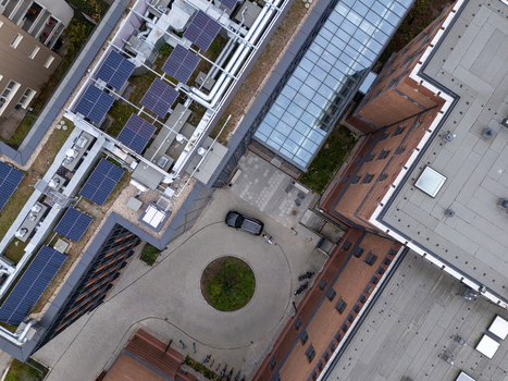 Aerial view of a modern building complex with solar panels on the rooftops a glass covered walkway and a circular courtyard with a tree in Gdansk Poland. Aerial view of a modern building complex with solar panels on the rooftops a glass covered walkway and a circular courtyard with a tree in Gdansk Poland.