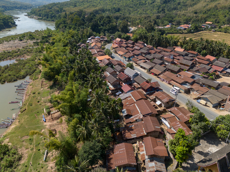 Aerial view of the village of Ban Hat Kho with traditional houses lush tropical trees and small boats moored along the Mekong River in Ban Hat Kho Luang Prabang Province Laos.
