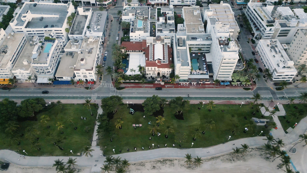 Aerial view of Miami Beach featuring lush palm trees in the park coastal walkways and urban architecture with hotels along the oceanfront in Miami Beach Florida United States. Aerial view of Miami Beach featuring lush palm trees in the park coastal walkways and urban architecture with hotels along the oceanfront in Miami Beach Florida United States.