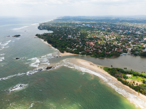 Aerial view of a scenic coastline featuring a river mouth meeting the ocean with sandy beaches and lush tropical vegetation in Matara Southern Province Sri Lanka. Aerial view of a scenic coastline featuring a river mouth meeting the ocean with sandy beaches and lush tropical vegetation in Matara Southern Province Sri Lanka.