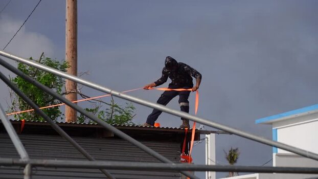View of a worker securing a roof in San Jose Northern Mariana Islands. View of a worker securing a roof in San Jose Northern Mariana Islands.