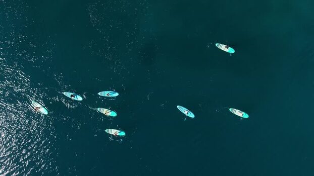 Aerial view of people paddling on sparkling aqua waves Losinj Croatia.