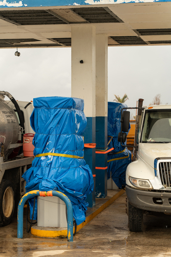 San Jose Tinian Northern Mariana Islands 05 July 2026 View of gas station pumps covered in blue tarps with trucks parked at a service station under an overcast sky. San Jose Tinian Northern Mariana Islands 05 July 2026 View of gas station pumps covered in blue tarps with trucks parked at a service station under an overcast sky.