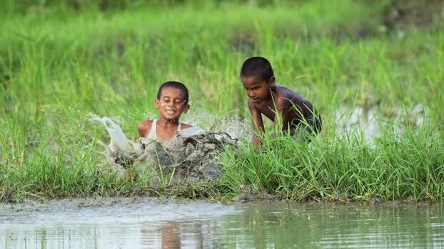 View of two boys playing in a muddy field in Bogura Bangladesh. View of two boys playing in a muddy field in Bogura Bangladesh.