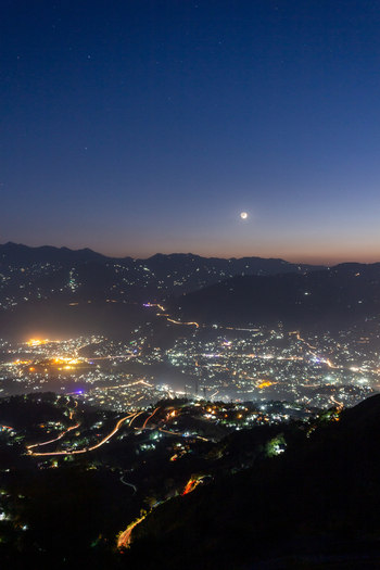 View of the sprawling city lights twinkling against the backdrop of the dark rolling mountains under the fading twilight sky Muzaffarabad Azad Kashmir Pakistan. View of the sprawling city lights twinkling against the backdrop of the dark rolling mountains under the fading twilight sky Muzaffarabad Azad Kashmir Pakistan.