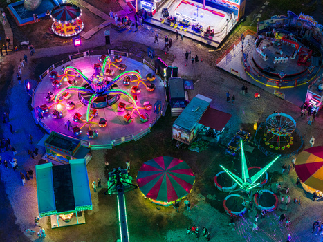 Aerial view of a vibrant fairground at night with illuminated amusement rides spinning attractions and colorful lights in Vilnius Vilnius County Lithuania. Aerial view of a vibrant fairground at night with illuminated amusement rides spinning attractions and colorful lights in Vilnius Vilnius County Lithuania.