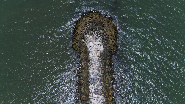 Aerial view of a stone breakwater extending into the turquoise ocean waters with gentle waves crashing against the rocks near Lekki Beach Road in Lekki Lagos Nigeria. Aerial view of a stone breakwater extending into the turquoise ocean waters with gentle waves crashing against the rocks near Lekki Beach Road in Lekki Lagos Nigeria.