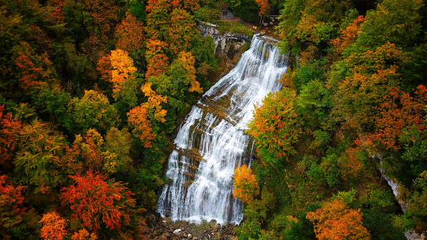 Aerial view of cascading waterfalls amidst a vibrant tapestry of autumn foliage where oranges and greens blend in nature s artistry Le Frasnois Bourgogne Franche Comt&eacute; France.