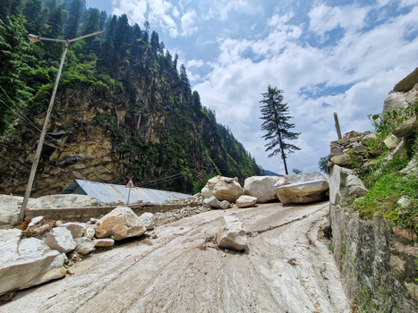 View of a road blocked by large boulders from a landslide in the mountainous terrain of Malana Himachal Pradesh India.
