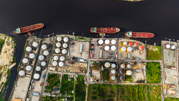 Aerial view of the industrial oil storage tank farm and cargo ships docked at the pier in Satellite Town Lagos Lagos Nigeria.