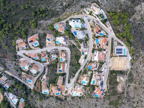 Aerial view of residential villas with swimming pools nestled along winding roads in the hillside landscape of Moraira Valencian Community Spain.