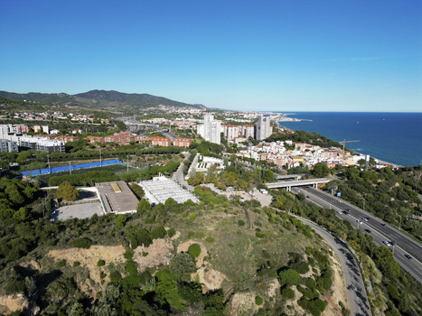 Aerial view of the coastal town of Montgat featuring residential buildings a highway green hills and the Mediterranean Sea under a clear blue sky in Montgat Catalonia Spain. Aerial view of the coastal town of Montgat featuring residential buildings a highway green hills and the Mediterranean Sea under a clear blue sky in Montgat Catalonia Spain.