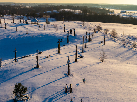 Aerial view of the Hill of Angels featuring tall wooden sculptures scattered across a snow covered landscape during sunset in Traku rajonas Vilniaus apskritis Lithuania. Aerial view of the Hill of Angels featuring tall wooden sculptures scattered across a snow covered landscape during sunset in Traku rajonas Vilniaus apskritis Lithuania.