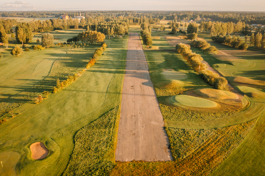 Aerial view of a golf course with green fairways sand bunkers and long tree shadows during golden hour in Valmiera Valmiera Latvija.