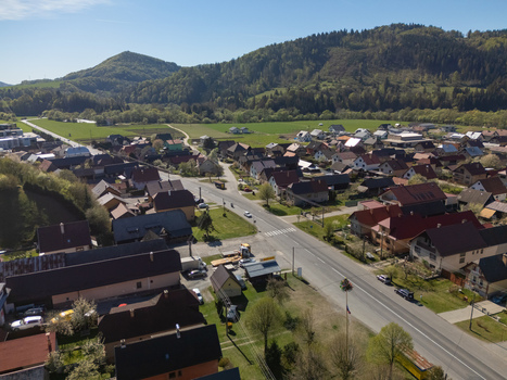 Aerial view of the village of Kriva featuring red roofed houses a main road and lush green fields against forested hills in Kriva Zilina Region Slovakia.