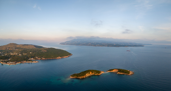 Aerial view of the Ksamil Islands surrounded by turquoise sea water and lush green vegetation with a ship on the horizon near Ksamil Vlore County Albania. Aerial view of the Ksamil Islands surrounded by turquoise sea water and lush green vegetation with a ship on the horizon near Ksamil Vlore County Albania.