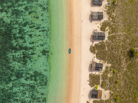Aerial view of Pink Beach with its unique pink sand turquoise waters coral reefs a small boat and wooden huts along the shore in East Nusa Tenggara Indonesia. Aerial view of Pink Beach with its unique pink sand turquoise waters coral reefs a small boat and wooden huts along the shore in East Nusa Tenggara Indonesia.