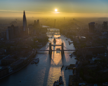 Aerial view of Tower Bridge and The Shard at sunset with the River Thames reflecting golden light through a hazy city skyline London Greater London United Kingdom. Aerial view of Tower Bridge and The Shard at sunset with the River Thames reflecting golden light through a hazy city skyline London Greater London United Kingdom.