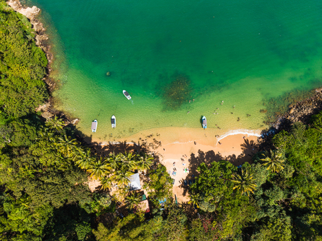 Aerial view of Jungle Beach featuring turquoise waters small boats anchored near the shore and lush tropical greenery in Unawatuna Sri Lanka. Aerial view of Jungle Beach featuring turquoise waters small boats anchored near the shore and lush tropical greenery in Unawatuna Sri Lanka.