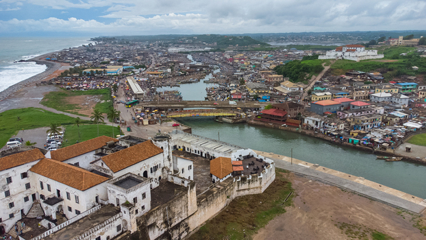 Aerial view of Elmina Castle with its historic white walls and orange tiled roofs overlooking the river and coastal town of Elmina Central Region Ghana. Aerial view of Elmina Castle with its historic white walls and orange tiled roofs overlooking the river and coastal town of Elmina Central Region Ghana.
