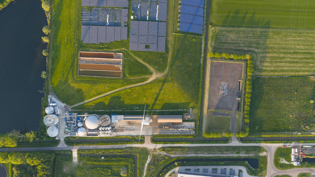 Aerial view of Wabico BV biogas plant featuring solar panel arrays industrial tanks and green fields under golden hour light in Waalwijk Noord Brabant Netherlands.