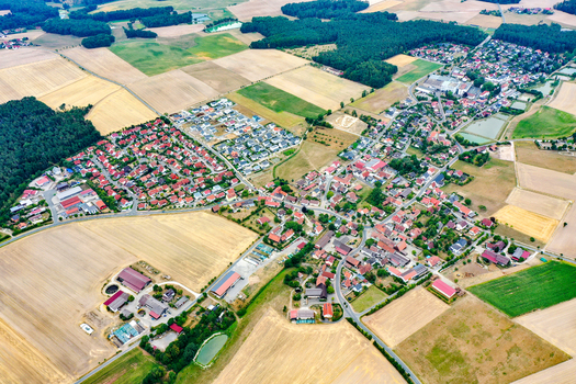 Aerial view of the village of Oberreichenbach with its red roofed houses nestled among vast agricultural fields and dense green forests in Oberreichenbach Bavaria Germany. Aerial view of the village of Oberreichenbach with its red roofed houses nestled among vast agricultural fields and dense green forests in Oberreichenbach Bavaria Germany.