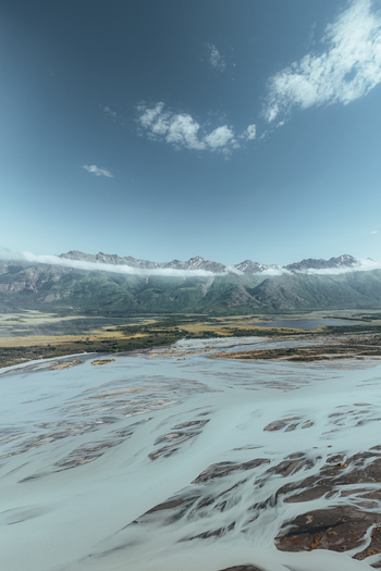 Aerial view of the braided glacial river winding through the Alaska Wilderness with snow capped mountains under a clear blue sky in Palmer Alaska United States. Aerial view of the braided glacial river winding through the Alaska Wilderness with snow capped mountains under a clear blue sky in Palmer Alaska United States.