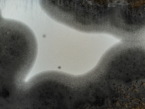 Aerial view of a serene body of water reflecting the sky embraced by dark textured banks in Kromslootpark Almere Flevoland Netherlands. Aerial view of a serene body of water reflecting the sky embraced by dark textured banks in Kromslootpark Almere Flevoland Netherlands.