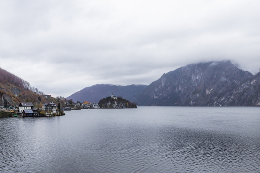 View of the historic village of Hallstatt and its iconic church overlooking the calm lake waters under a misty mountain landscape Hallstatt Upper Austria Austria. View of the historic village of Hallstatt and its iconic church overlooking the calm lake waters under a misty mountain landscape Hallstatt Upper Austria Austria.