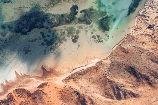 Aerial view of Detwah Lagoon featuring turquoise water coral reefs and sandy shores along the rocky arid landscape in Qalansiyah wa Abd Al Kuri Socotra Yemen. Aerial view of Detwah Lagoon featuring turquoise water coral reefs and sandy shores along the rocky arid landscape in Qalansiyah wa Abd Al Kuri Socotra Yemen.