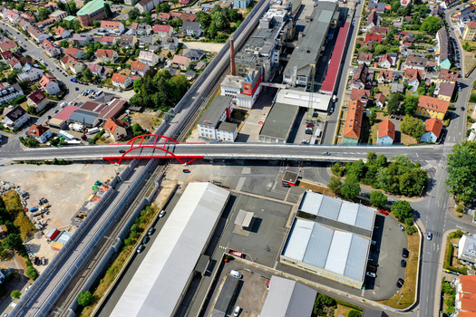 Aerial view of the red arched Piastenbrucke bridge spanning across railway lines and industrial complexes in Forchheim Bayern Germany.