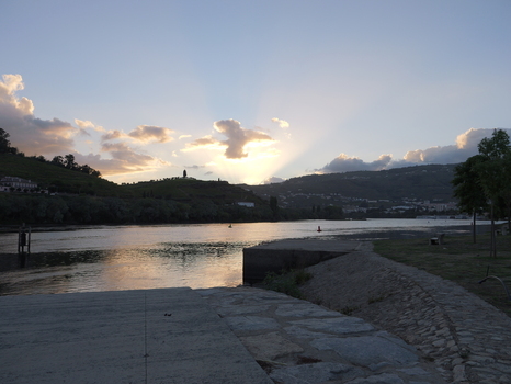 View of the Douro River at sunset with sunbeams breaking through clouds over the terraced hills in Peso da Regua Vila Real District Portugal.