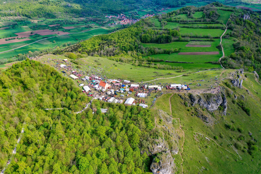 Aerial view of the Walberla hill featuring a festival with tents and a chapel surrounded by lush green forests and fields in Kirchehrenbach Bavaria Germany. Aerial view of the Walberla hill featuring a festival with tents and a chapel surrounded by lush green forests and fields in Kirchehrenbach Bavaria Germany.