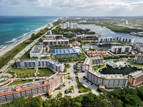 Aerial view of coastal residential complexes with tennis courts swimming pools and a marina near the sandy beach and blue ocean in Boca Raton Florida United States. Aerial view of coastal residential complexes with tennis courts swimming pools and a marina near the sandy beach and blue ocean in Boca Raton Florida United States.