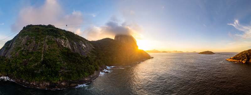Aerial view of Sugarloaf Mountain at sunset with golden light hitting the granite peak clouds and the Atlantic Ocean in Rio de Janeiro State of Rio de Janeiro Brazil. Aerial view of Sugarloaf Mountain at sunset with golden light hitting the granite peak clouds and the Atlantic Ocean in Rio de Janeiro State of Rio de Janeiro Brazil.