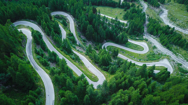 Aerial view of a winding serpentine road with hairpin turns through a dense green coniferous forest Heremence Valais Switzerland. Aerial view of a winding serpentine road with hairpin turns through a dense green coniferous forest Heremence Valais Switzerland.
