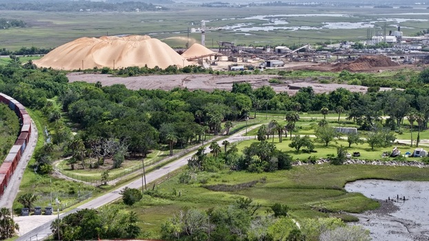 Aerial view of contrasting textures and tones between the industrial zone and the natural marshlands with a train winding through the landscape Fernandina Beach Florida United States. Aerial view of contrasting textures and tones between the industrial zone and the natural marshlands with a train winding through the landscape Fernandina Beach Florida United States.
